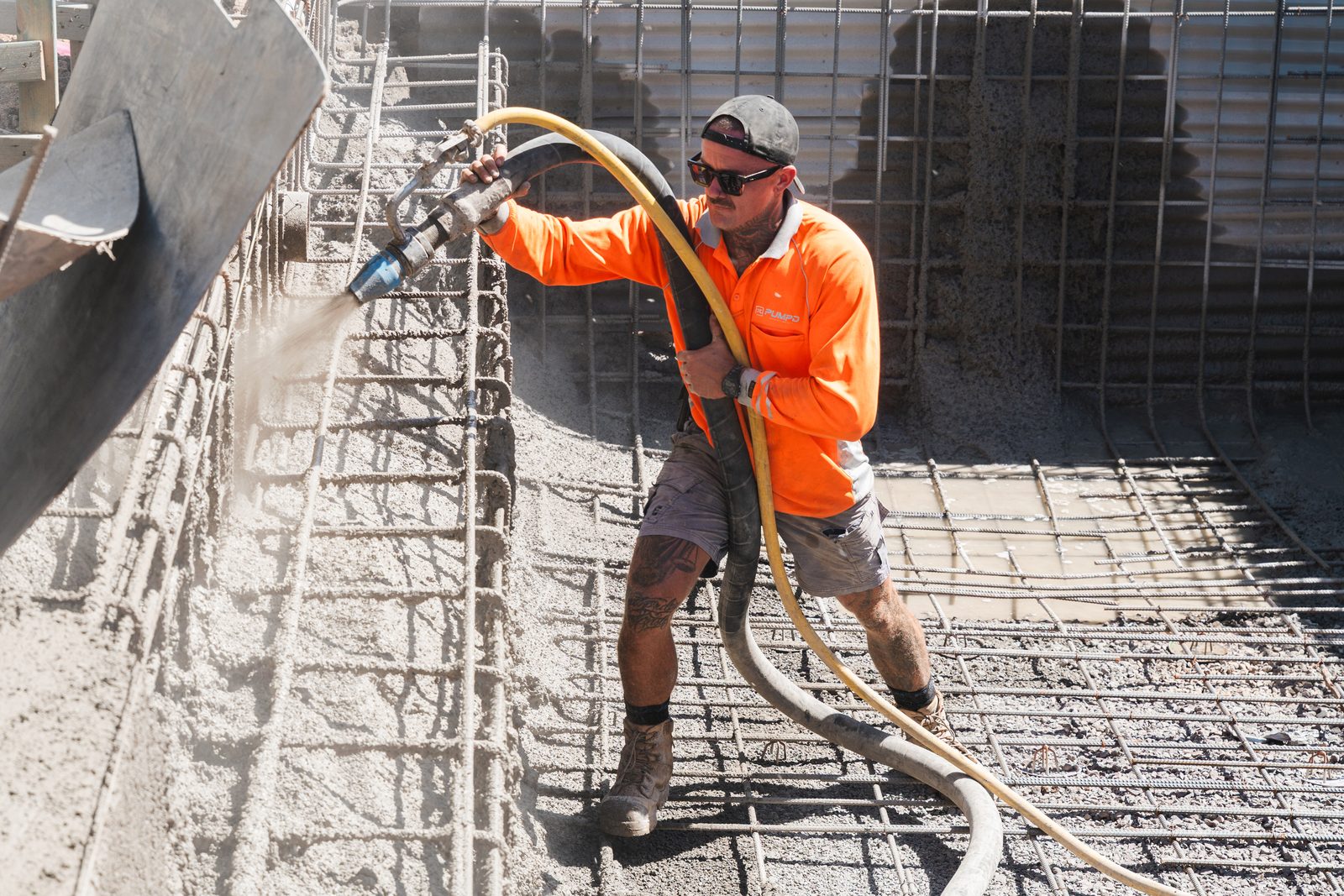 A Pumpd nozzleman spraying wet-mix shotcrete onto a reinforced vertical face