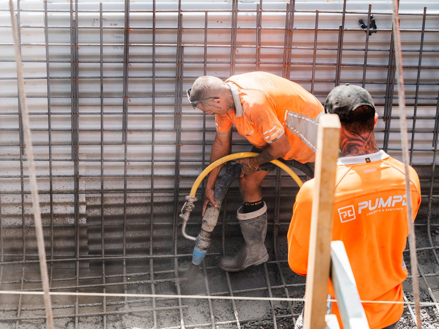Two Pumpd crew spraying shotcrete inside a tall reinforced wall cage